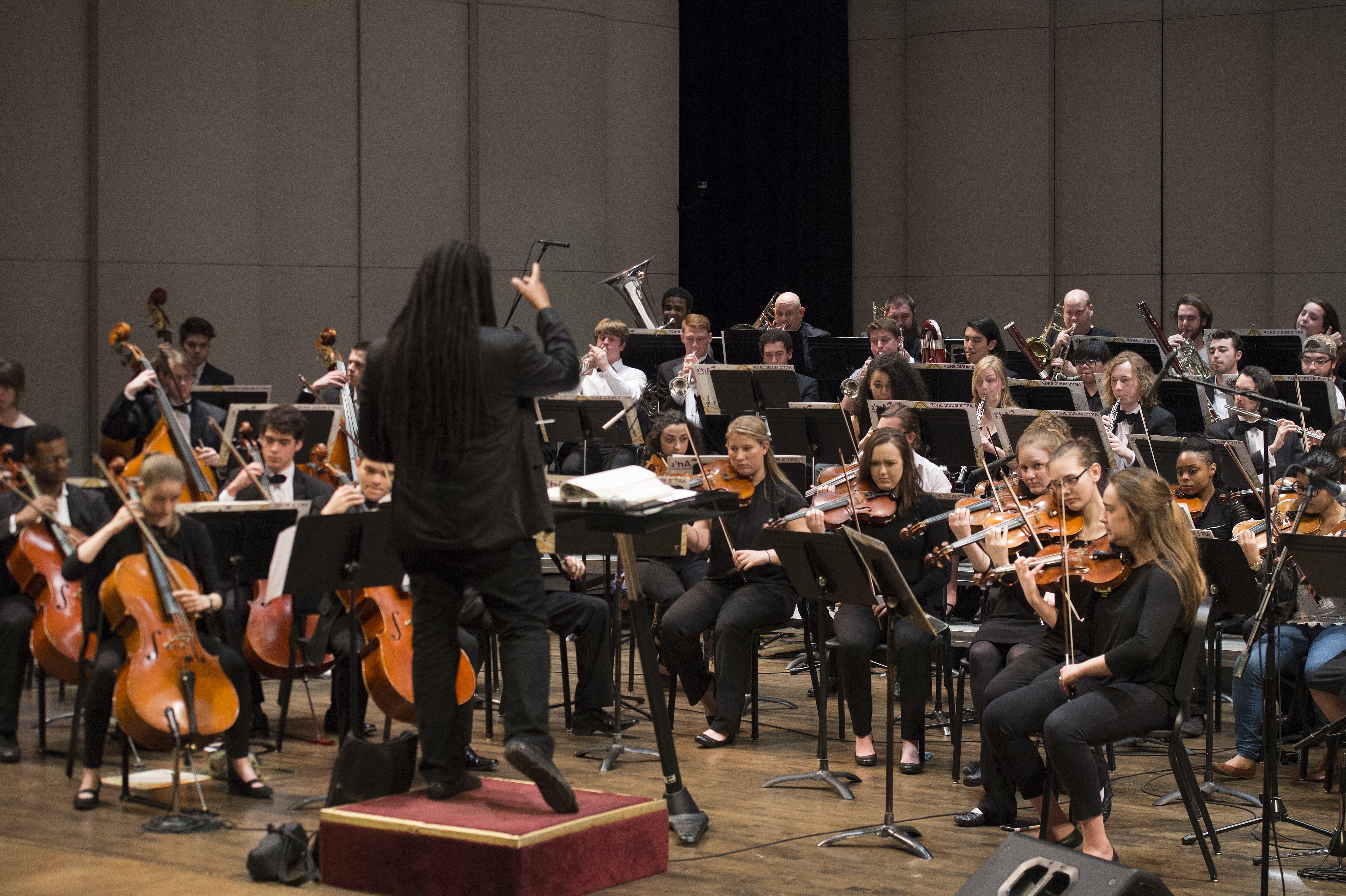 A photograph of Dr. Jean Montès leading a performance of the Loyola Symphony Orchestra.